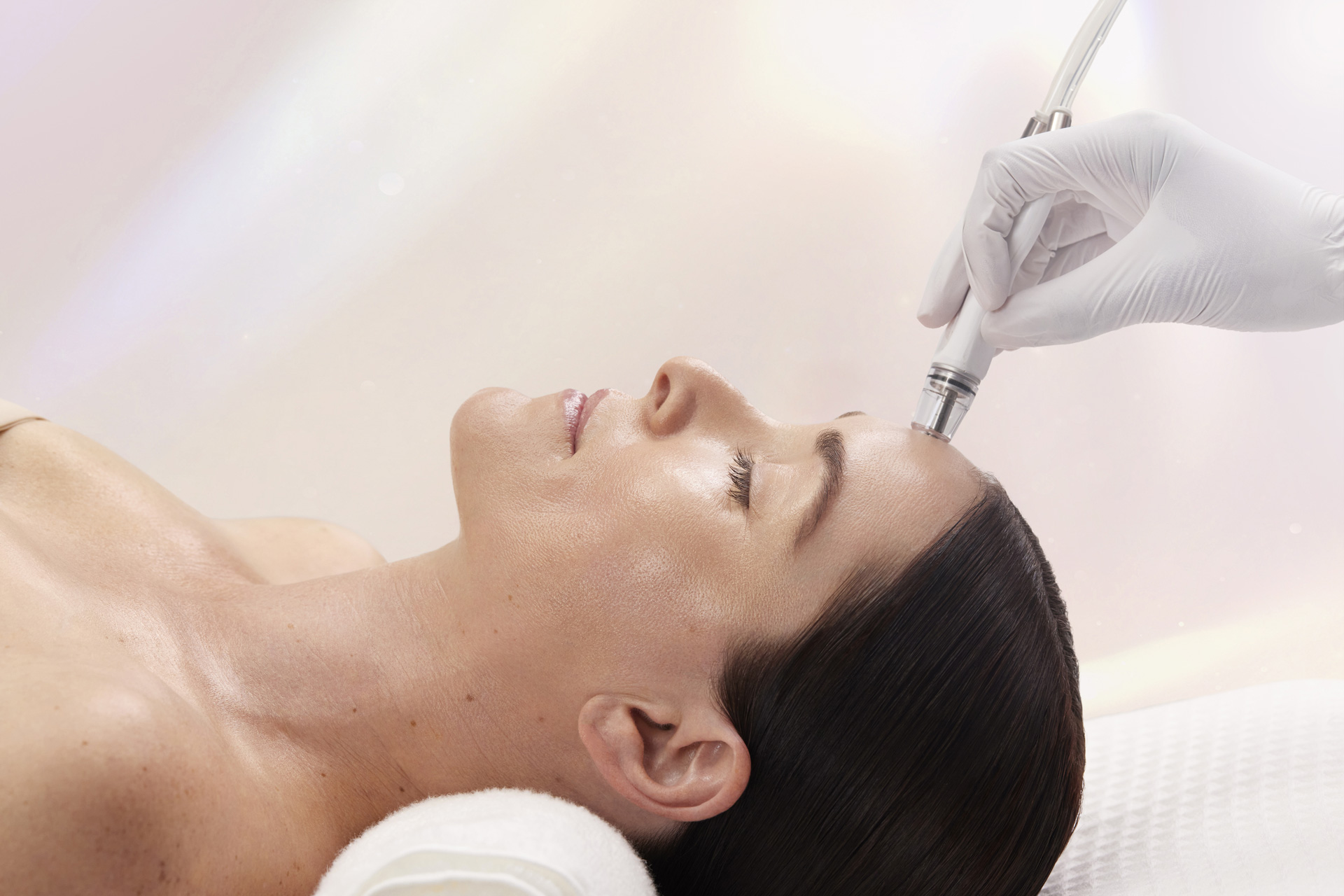 Female receiving diamond glow treatment on forehead